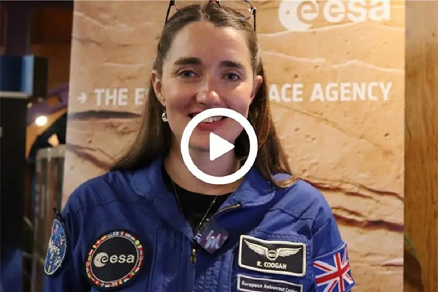 young female astronaut in blue uniform smiling